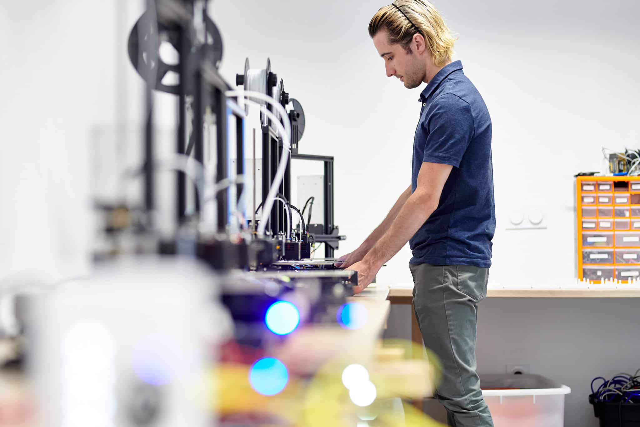 Technicien utilisant des imprimantes 3D dans un laboratoire.